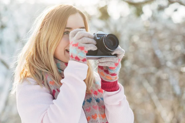 Jovem caucasiano atraente menina loira em suéter rosa e cachecol de malha detém câmera de filme retro no parque de inverno ao ar livre — Fotografia de Stock