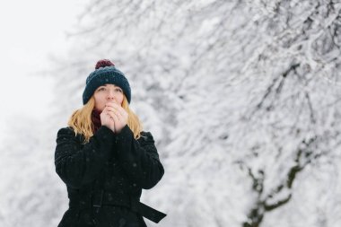 Siyah palto ve kırmızı örme eşarp genç Beyaz sarışın kız kış parkta yürüyor