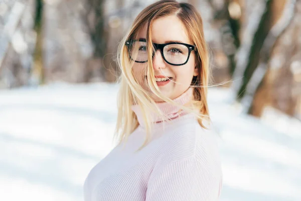 Jovem caucasiano atraente menina loira em suéter rosa e cachecol de malha detém no parque de inverno ao ar livre — Fotografia de Stock