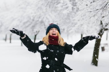 Siyah palto ve kırmızı örme eşarp genç Beyaz sarışın kız kış parkta yürüyor