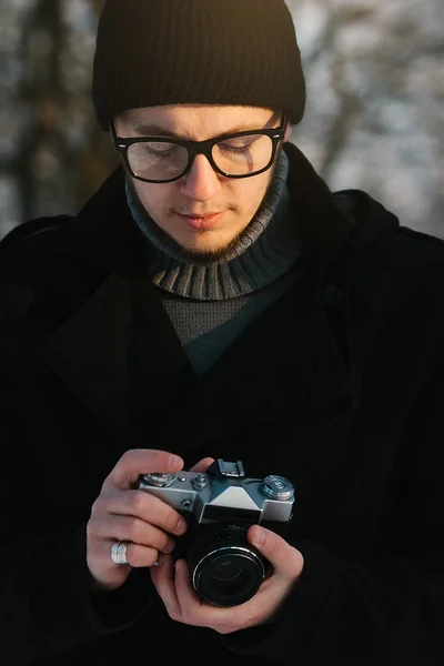 黒コートを着た若い男の手で古いレトロなビンテージ フィルム カメラを保持します。 — ストック写真