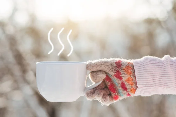 Młoda dziewczyna trzyma kubek herbaty w dłoni w winter park — Zdjęcie stockowe