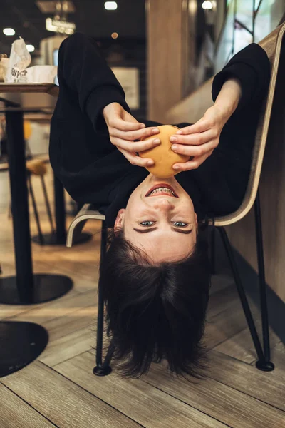 Beautiful Brunette Girl in Black Pullover Holding a Tasty Burger Head Down — Stock Photo, Image