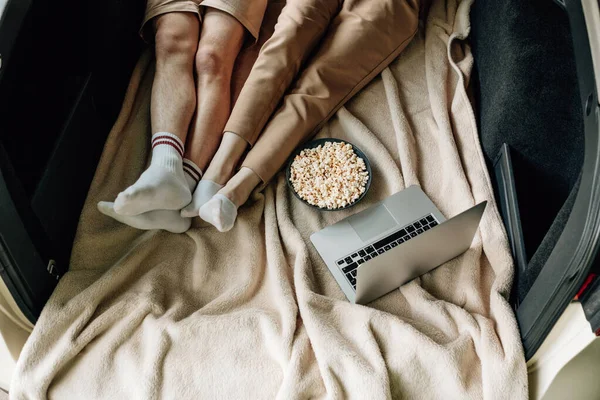 Genç, mutlu, beyaz tişörtlü bir çift. Araba bagajında dizüstü bilgisayar ve patlamış mısırla oturuyor. Hafta sonu şehrin dışında, tatillerde ve yolculukta.