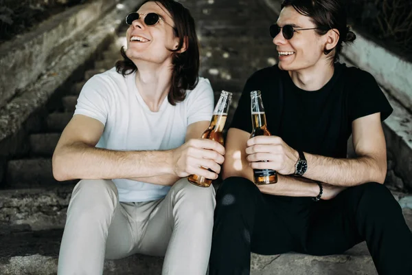 Due fratelli gemelli alla moda che si divertono a bere birra sulle scale — Foto Stock