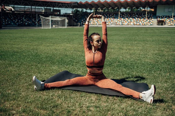 Retrato de una chica deportiva vestida con ropa deportiva haciendo estiramientos Ejercicio y entrenamiento en el estadio de la ciudad, concepto de estilo de vida saludable — Foto de Stock