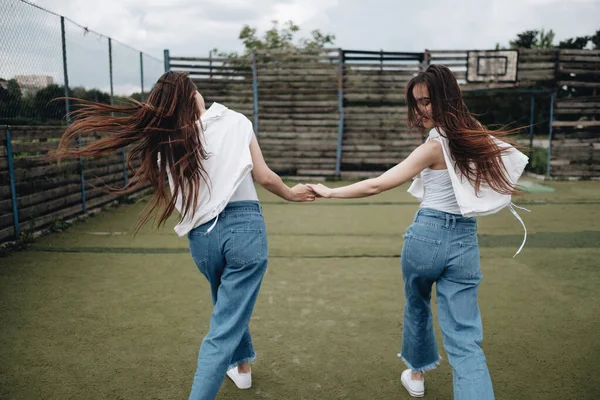 Retrato de duas jovens gêmeas morena irmãs vestidas de jeans e camiseta branca, Melhores amigos sempre conceito — Fotografia de Stock