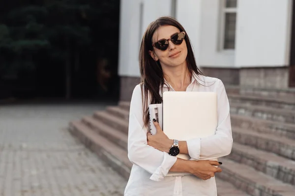 Retrato de una chica de moda vestida con vaqueros y camisa blanca que sostiene el ordenador portátil, trabajador independiente, dama de negocios, concepto de poder de la mujer — Foto de Stock