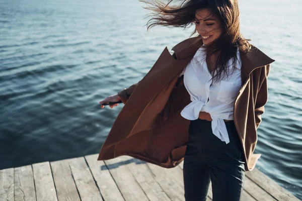 Menina bonita e elegante em casaco Caminhando na praia da primavera ao pôr do sol — Fotografia de Stock