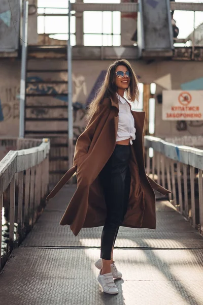 Belle jeune fille élégante en manteau marchant dans la plage de printemps au coucher du soleil — Photo