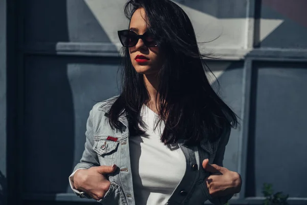 Piękna brunetka dziewczyna w okulary przeciwsłoneczne białe spodnie i dżinsy Jacket, czerwona szminka — Zdjęcie stockowe