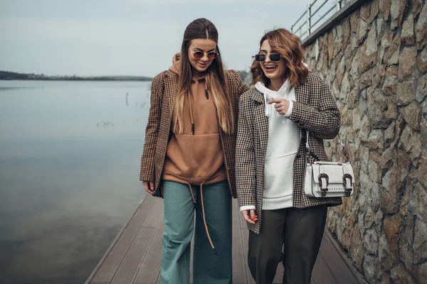 Πορτρέτο των δύο κορίτσια μόδας, καλύτεροι φίλοι σε εξωτερικούς χώρους, φορώντας κομψό μπουφάν, περπάτημα κοντά στη λίμνη — Φωτογραφία Αρχείου