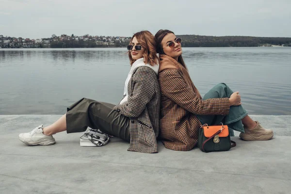 Πορτρέτο των δύο κορίτσια μόδας, καλύτεροι φίλοι σε εξωτερικούς χώρους, φορώντας κομψό μπουφάν, περπάτημα κοντά στη λίμνη — Φωτογραφία Αρχείου
