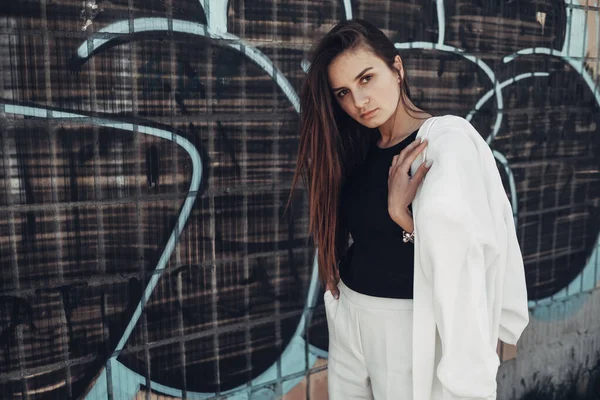 Porträtt av Mode Snygg flicka i vit kostym Posing nära graffitiväggen — Stockfoto