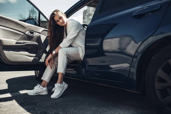Mode snygg tjej i vit kostym poserar nära den blå bilen — Stockfoto