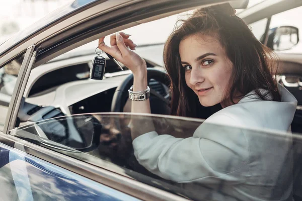 Модная стильная девушка-водитель в белом костюме сидит в машине — стоковое фото