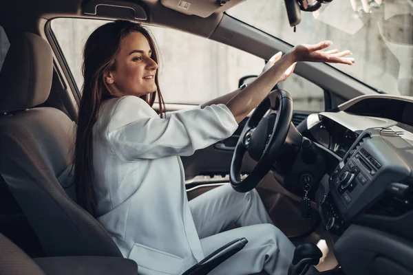 車の中に座って白いスーツのファッションスタイリッシュなドライバーの女の子 — ストック写真