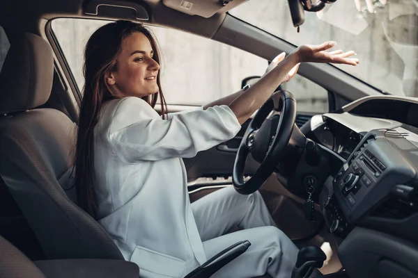 Moda elegante conductor chica en traje blanco sentado en el coche — Foto de Stock