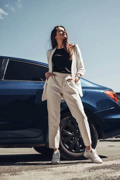 Retrato de moda elegante menina de terno branco posando perto do carro azul — Fotografia de Stock