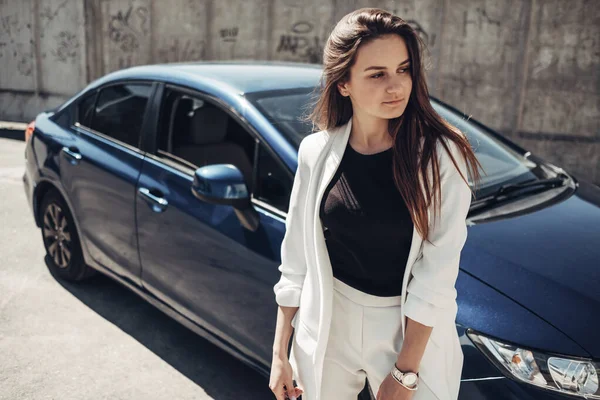 Moda menina elegante em terno branco posando perto do carro azul — Fotografia de Stock