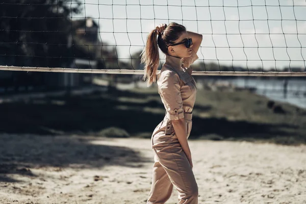 Retrato de chica con estilo viste overoles de mujer posando en la playa de arena — Foto de Stock
