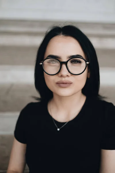 Porträtt av Söt brunett flicka i svart T-shirt i glasögon — Stockfoto