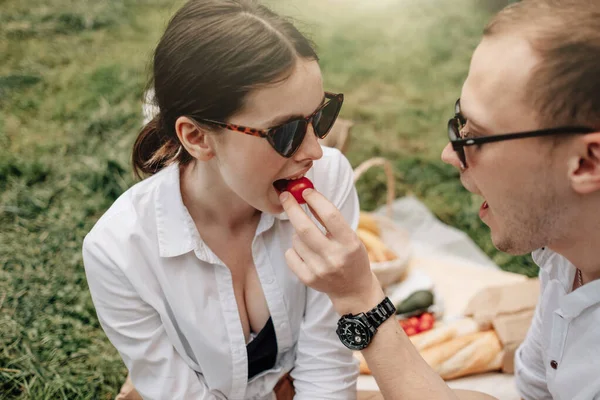 Pareja feliz joven vestida como en camiseta blanca divirtiéndose en el picnic, fin de semana fuera de la ciudad, concepto de vacaciones — Foto de Stock