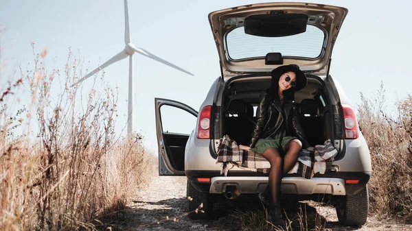 幸せな旅行の女の子背景に電動風力タービン発電機でフィールド道路上の車の旅を楽しむ — ストック写真