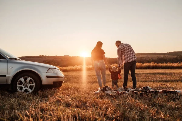 행복 한 어린 가족 엄마와 아빠, 어린 아들 과 함께 화창 한 날해 가 지면 야외에서 차를 타고 여름 소풍을 즐기는 것 — 스톡 사진