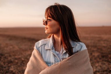 Beyaz gömlekli ve kot ceketli güzel bir kızın portresi, Sunset 'te şehrin dışında iyi vakit geçiriyor.