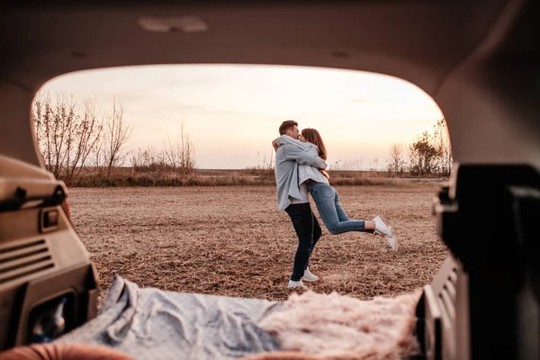 Beyaz Gömlekli ve Kot Giyen Genç Mutlu Çift Yeni Araba Bagajlarında Oturuyor, Sahada Güzel Günbatımı, Tatil ve Seyahat Konsepti
