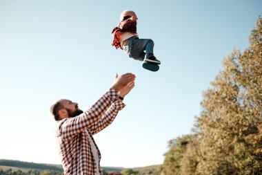 Küçük oğluyla mutlu bir baba. Yaz haftasının tadını çıkarıyor. Güneşli gün batımında şehrin dışındaki kırda.