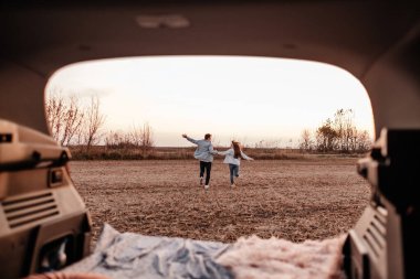 Beyaz Gömlekli ve Kot Giyen Genç Mutlu Çift Yeni Araba Bagajlarında Oturuyor, Sahada Güzel Günbatımı, Tatil ve Seyahat Konsepti