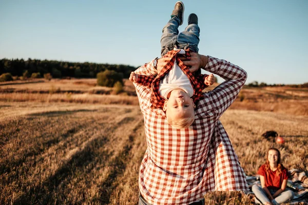 Jovem família feliz mãe e pai com seu filhinho desfrutando verão fim de semana piquenique fora da cidade no campo no pôr do sol dia ensolarado, conceito de tempo de férias — Fotografia de Stock