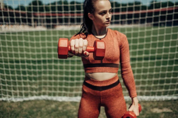 한 스포츠 운동복을 입은 한 건강 한 여자의 그림 덤벨을 가지고 운동을 하고 도시 경기장에서 훈련을 받는 모습, 건강 한 생활 방식의 개념 — 스톡 사진