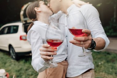 Beyaz tişörtlü genç mutlu çift arabanın yanında eğleniyor, hafta sonu şehir dışında, tatiller ve yolculuk konsepti.