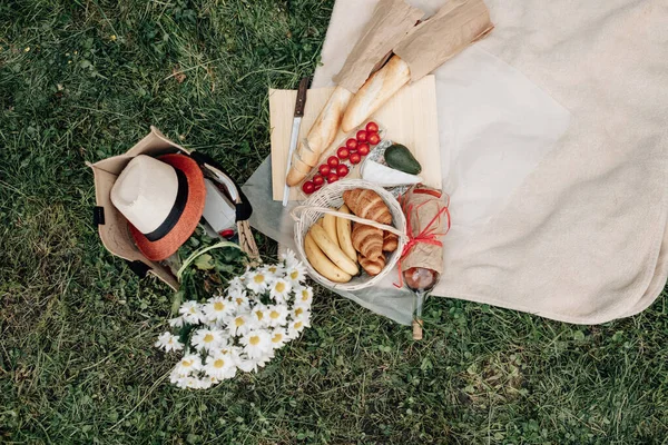 Pakiet piknikowy i kosz z rogalikiem i kawy i kwiatów leży na trawie, Koncepcja pikniku — Zdjęcie stockowe