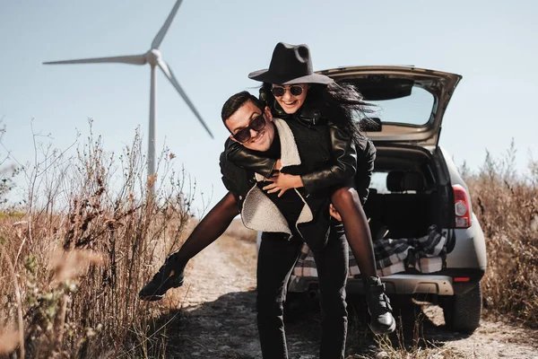 Happy Traveling Pasangan Menikmati Perjalanan Mobil di Lapangan Jalan dengan Angin Listrik Turbin Power Generator di Latar Belakang — Stok Foto