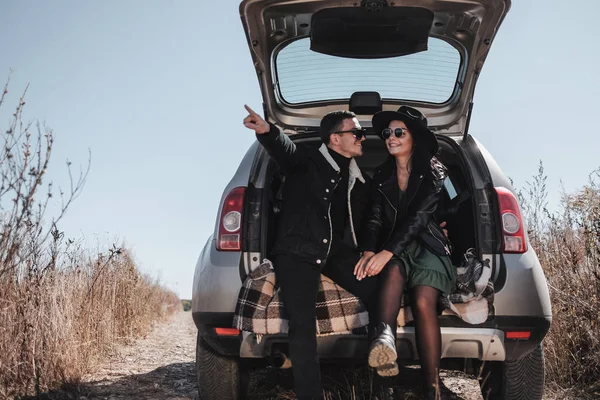 Couple voyageur heureux habillé en noir Vêtements élégants Profitant d'un voyage en voiture sur la route de campagne, concept de vacances — Photo