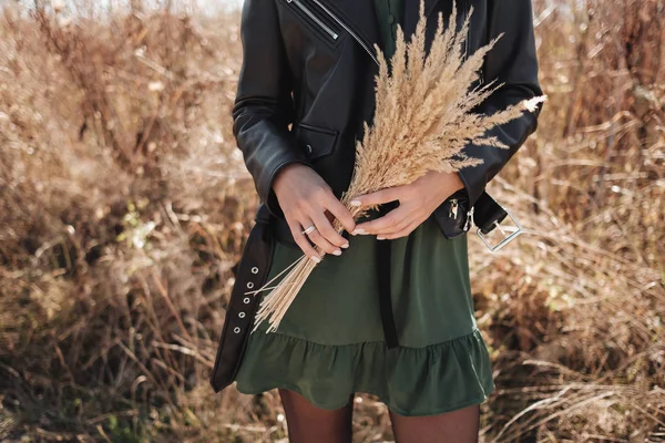 Retrato de una chica vestida con ropa negra elegante en el campo sostiene un ramo de orejas de trigo — Foto de Stock
