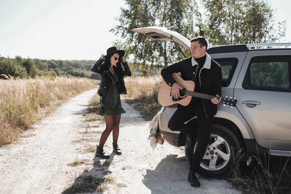 Siyah Giysili Mutlu Seyahat Çifti Saha Yolu 'nda Yolculuk, Gitar Çalan Adam, Tatil Konsepti — Stok fotoğraf