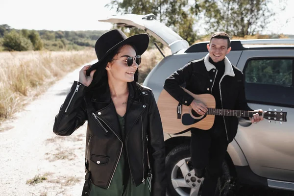 Siyah Giysili Mutlu Seyahat Çifti Saha Yolu 'nda Yolculuk, Gitar Çalan Adam, Tatil Konsepti — Stok fotoğraf