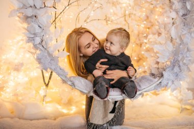 Noel temalı bir odada annesiyle birlikte küçük bir çocuğun portresi.