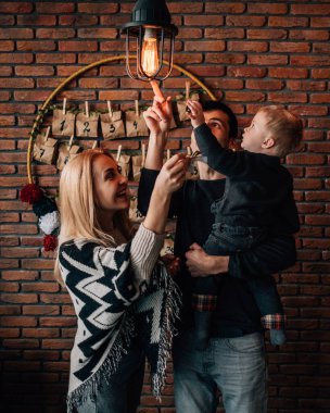 Anne ve babasının portresi ve Noel temalı odada oynayan küçük bir çocuk.