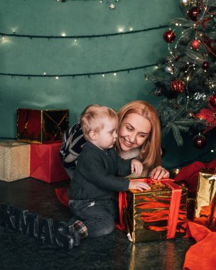 Noel temalı bir odada annesiyle birlikte küçük bir çocuğun portresi.