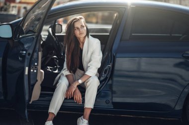 Mavi Arabanın Yanında Poz Veren Beyaz Takım Elbiseli Moda Şık Kız