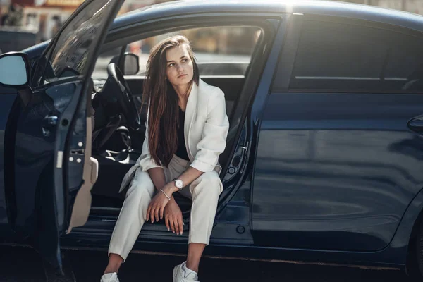 Moda stylowa dziewczyna w białym garniturze pozowanie w pobliżu Blue Car — Zdjęcie stockowe
