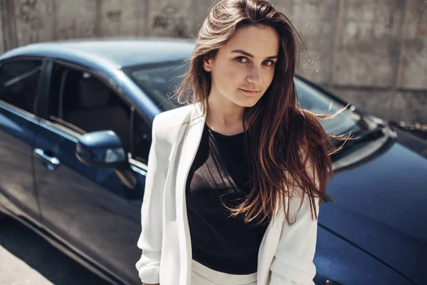 Moda menina elegante em terno branco posando perto do carro azul — Fotografia de Stock