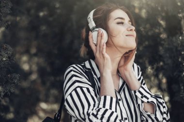Beyaz Çizgili Şık Elbiseli Genç Güzel Kızın Açık Yaz Portresi Kulaklıkla Müzik Dinliyor