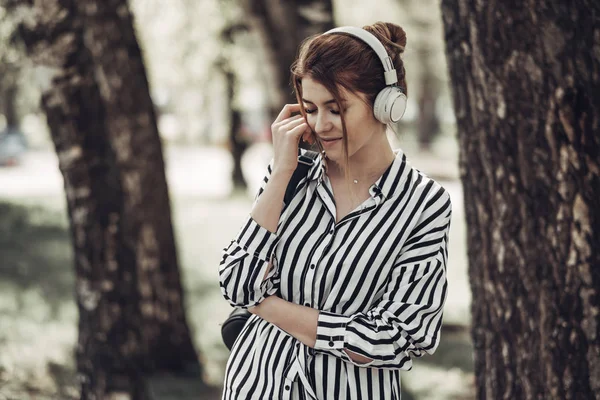 Outdoor Summer Portrait of Young Beautiful Girl in White Striped Stylish Dress Listens Music in Headphones — Stock Photo, Image